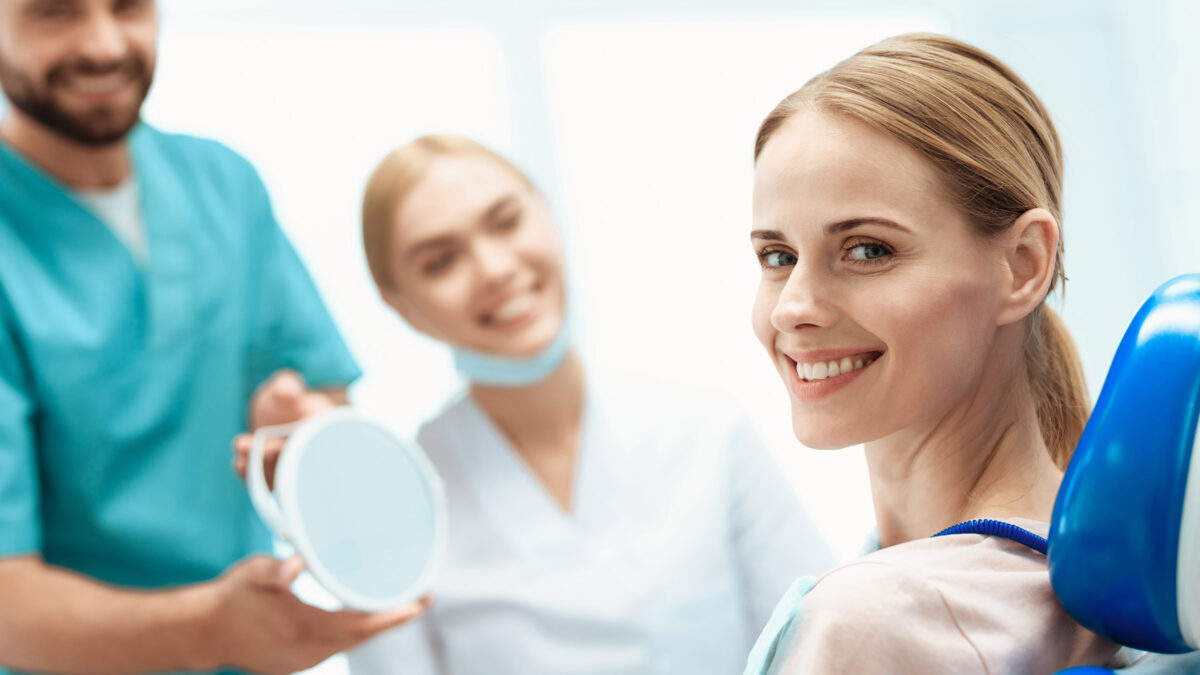 happy blond Aria Dental female patient smiling at camera