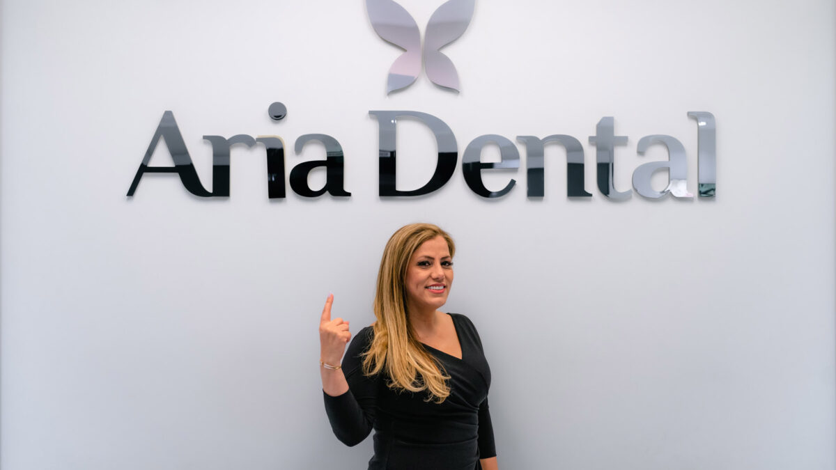 Dr. Maryam Horiyat pointing at Aria Dental Logo