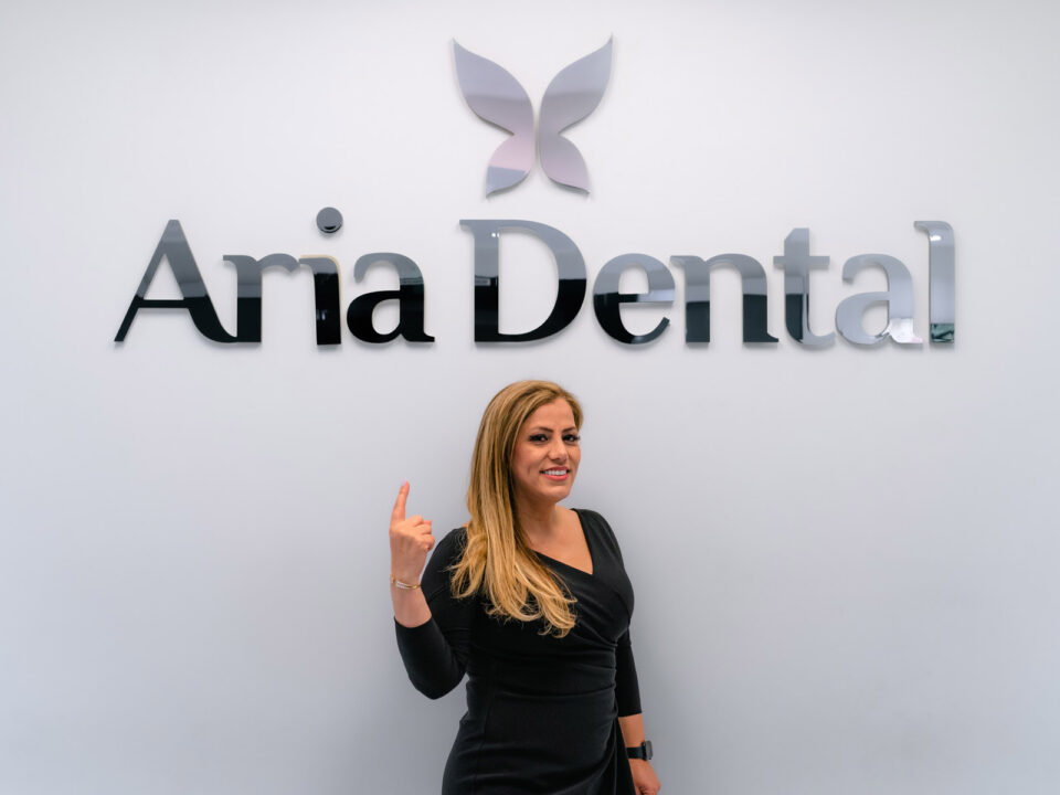 Dr. Maryam Horiyat pointing at Aria Dental Logo