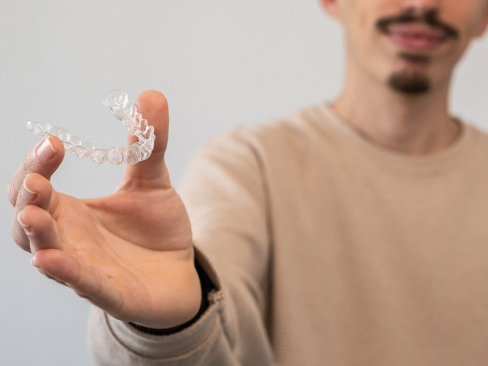 young man holding Invisalign retainer