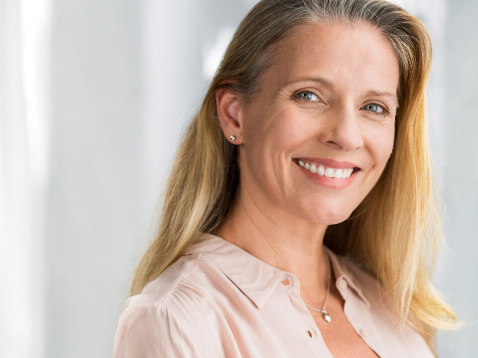 middle aged woman with zirconia dental implant installed smiling