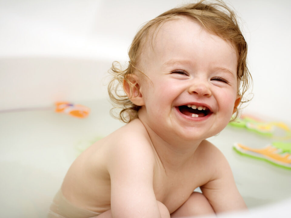 a baby laughing in bath tub