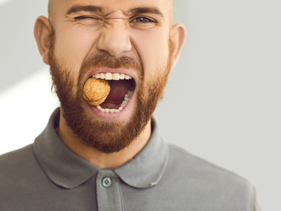 a man trying to chew a wallnut