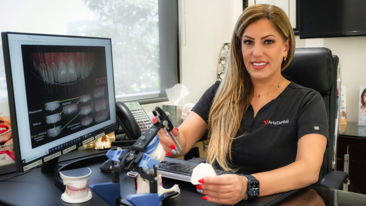 Dr. Maryam Horiyat smiling behind her desk at Aria Dental office