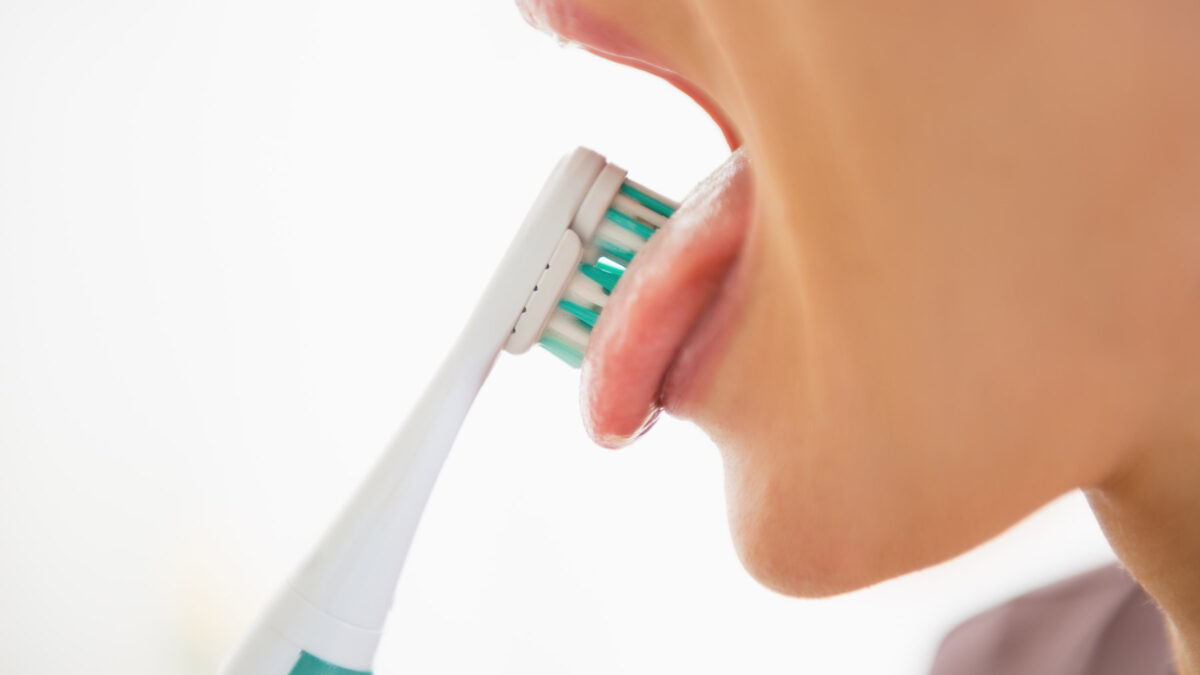a young female Aria Dental patient brushing her tongue