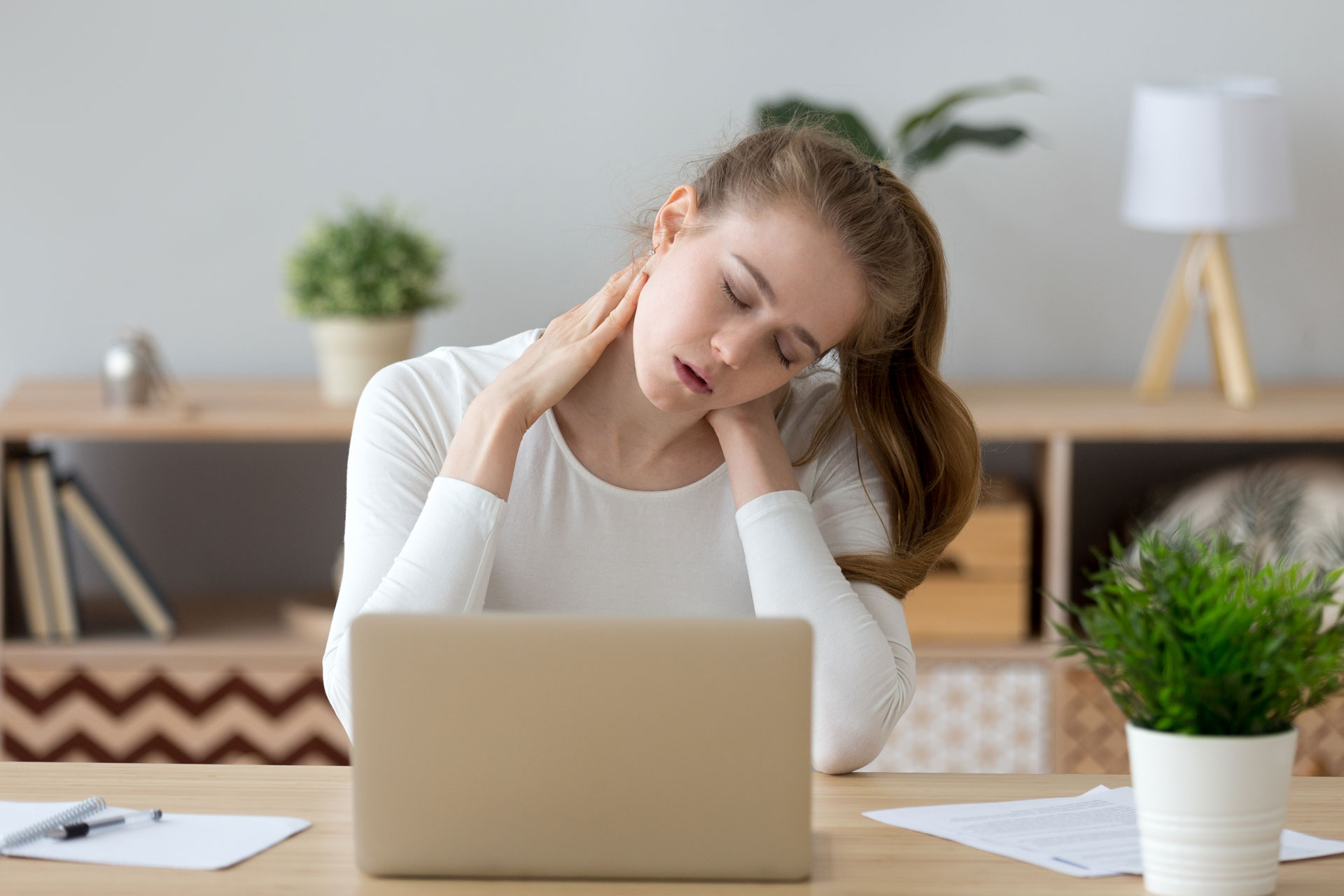 woman behind her laptop suffering from neck pain