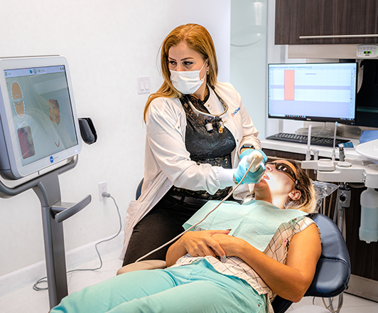 Dr. Maryam Horiyat working in office and scanning patient teeth