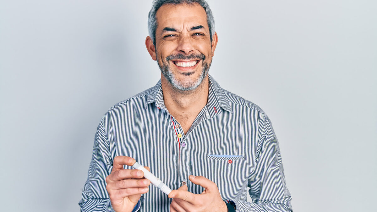 happy middle aged man testing his blood sugar