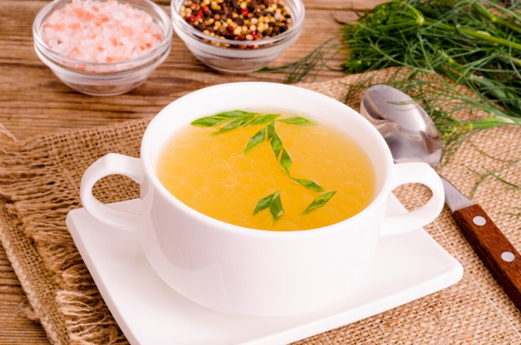 Top 25 Soft Foods to Eat After Oral Surgery for Faster Healing 1 Chicken broth soup in white plate.