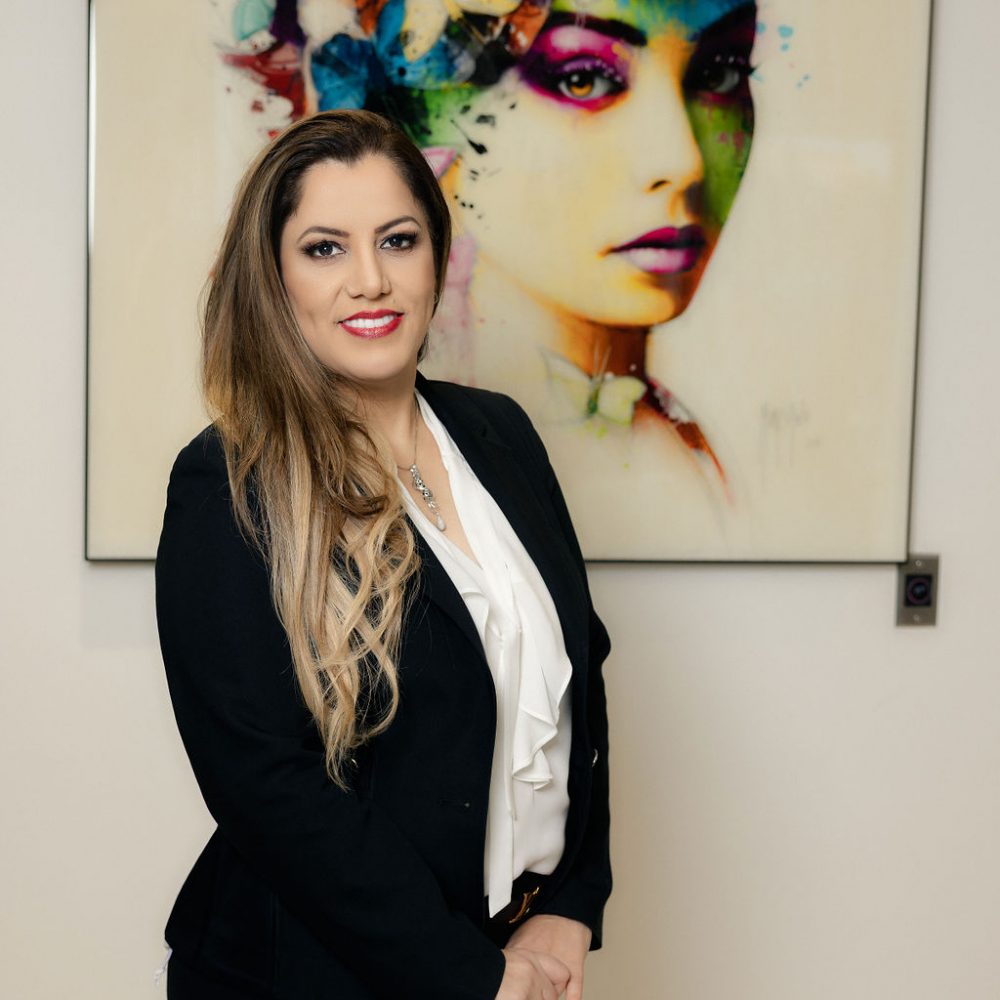 Dr. Maryam Horiyat in front of beautiful picture of an abstract painting of a woman in office